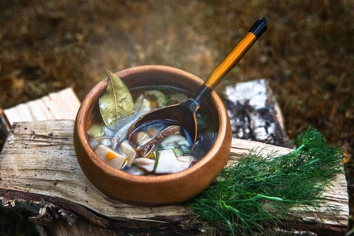 Zupa borowikowa na drewnianym talerzu z ziemniakami i marchewką