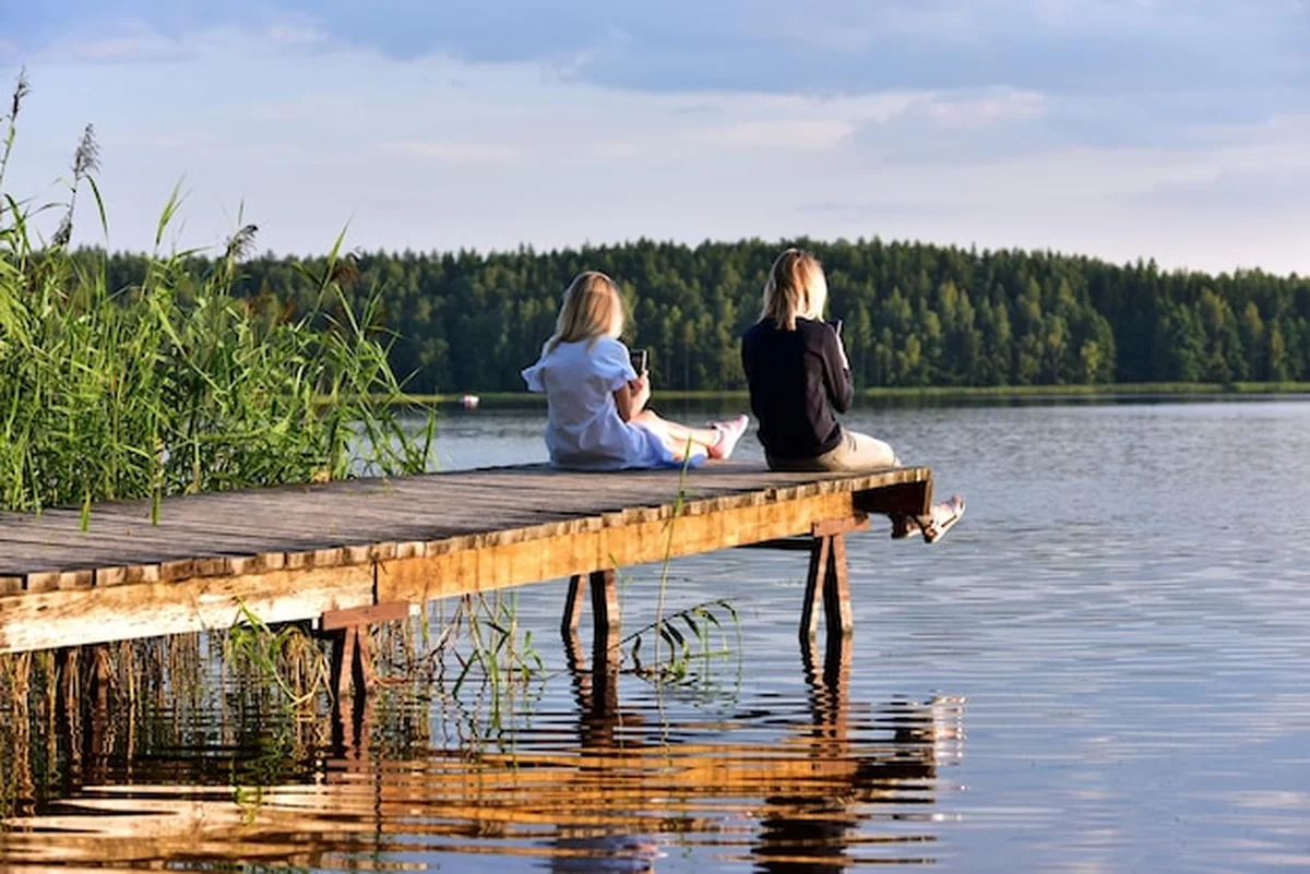 Ludzie siedzą nad jeziorem pod niebem