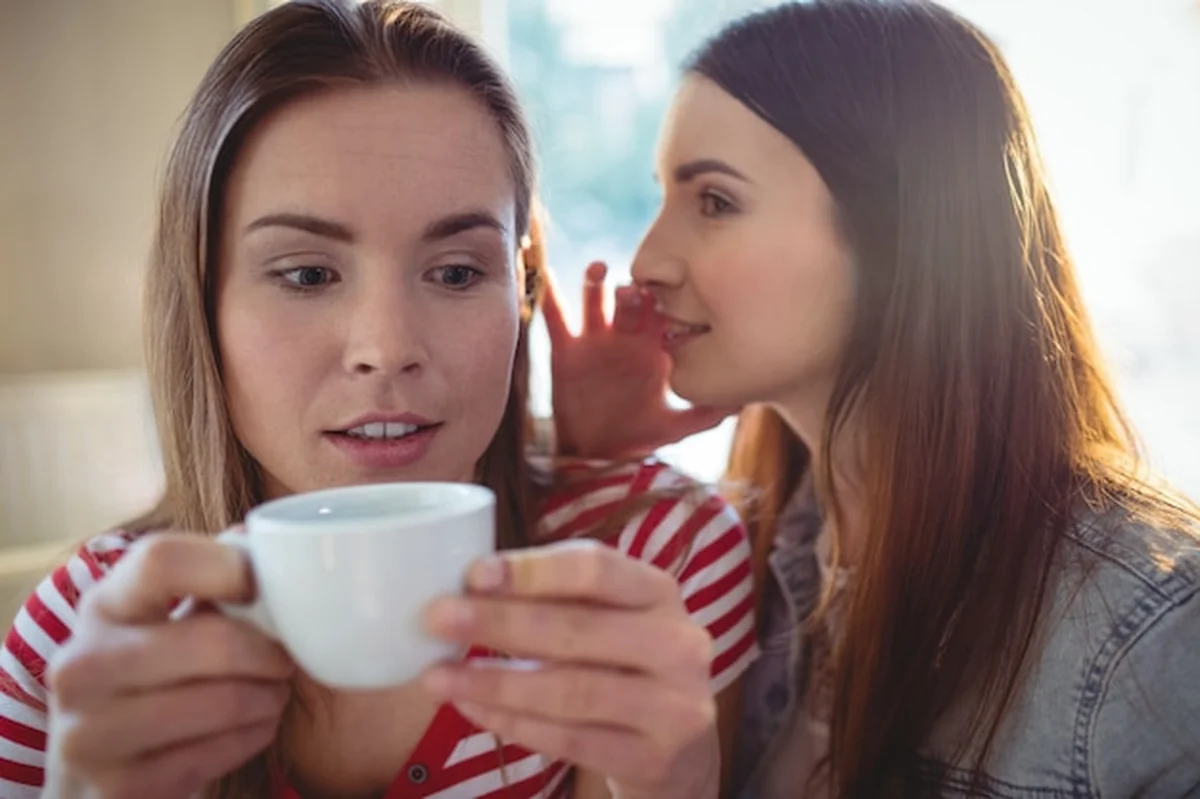 Kobieta szepcząca do przyjaciela w kawiarni