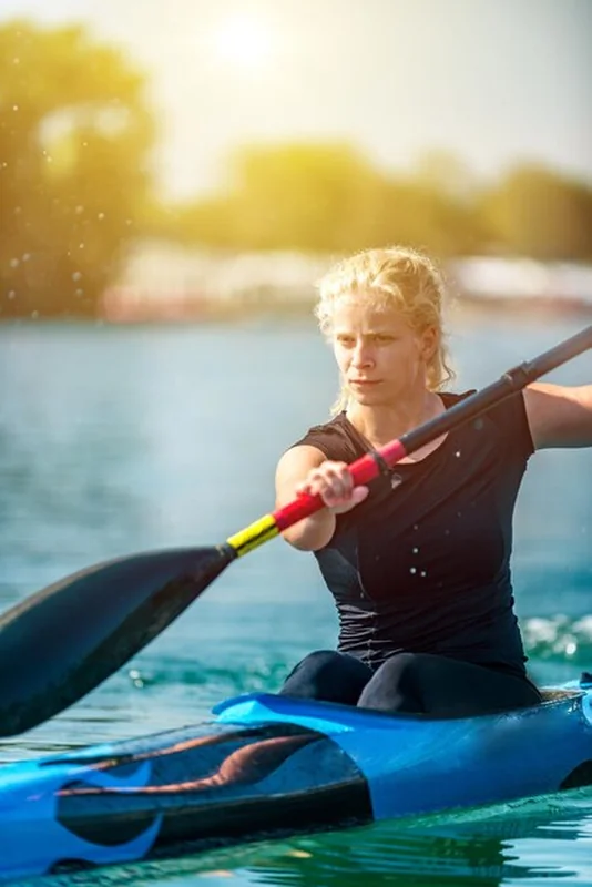 Lekkoatletka trenująca kajakarstwo po jeziorze