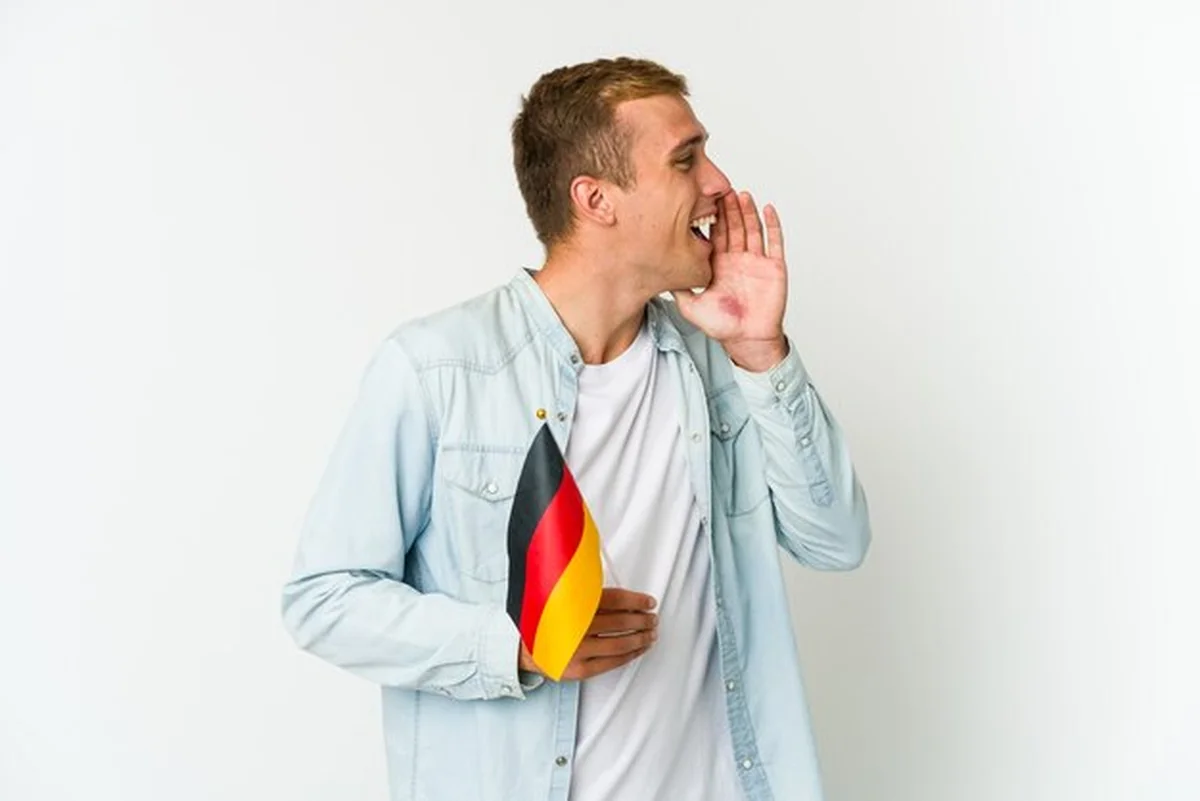 Młody mężczyzna trzyma niemiecką flagę, krzyczy na białym tle