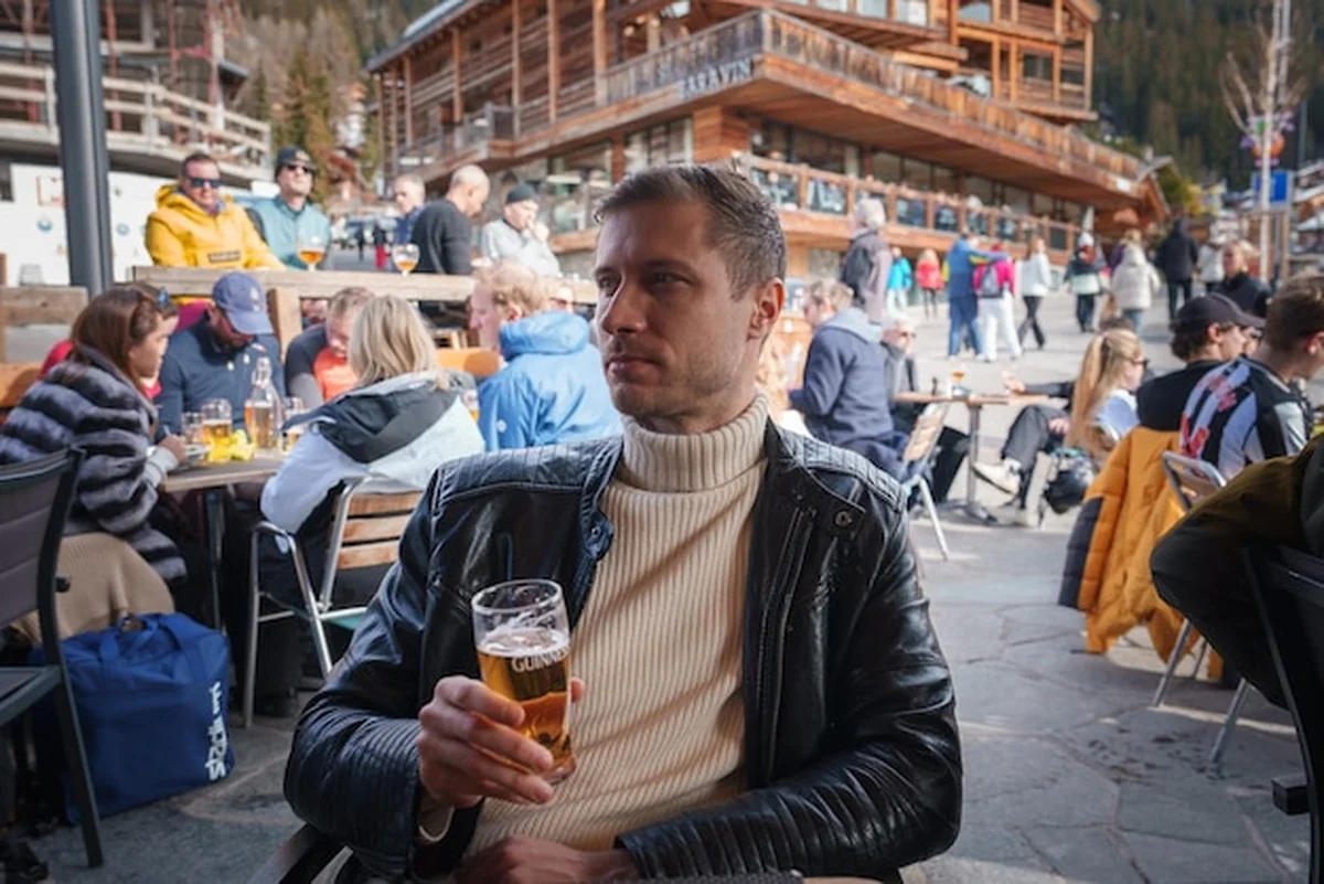 Mężczyzna trzymający piwo z logo Guinnessa na zewnątrz