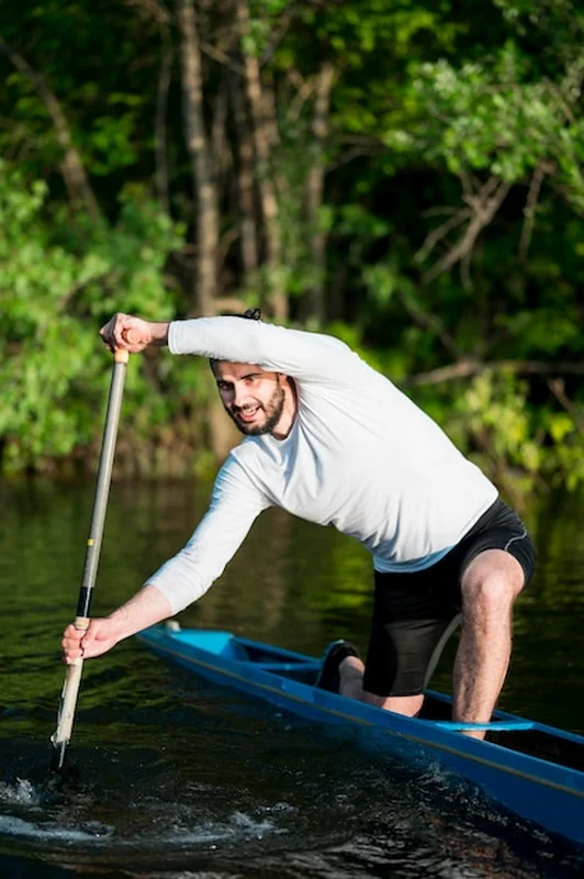 Mężczyzna w kajaku wioślujący na wodzie