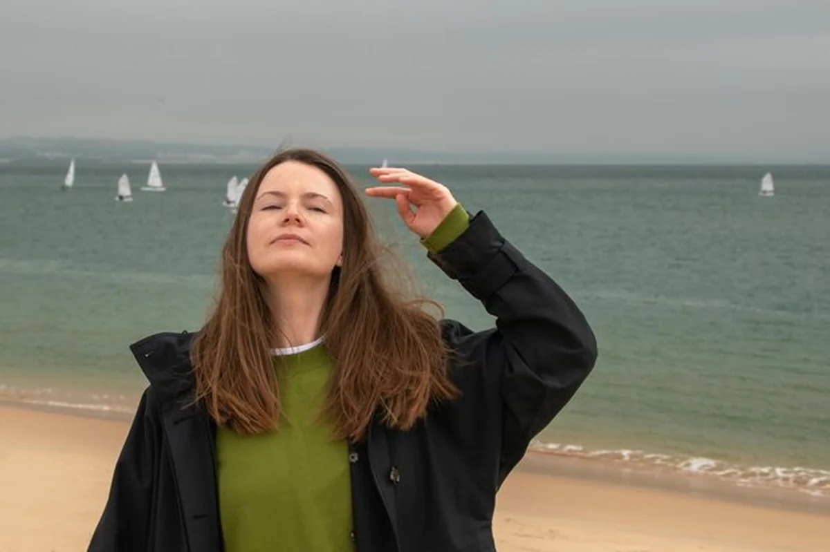 Młoda kobieta z długimi brązowymi włosami na plaży w deszczowy dzień