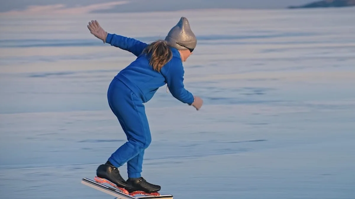Dziecko jeździ na łyżwach zimą w niebieskim garniturze i okularach sportowych