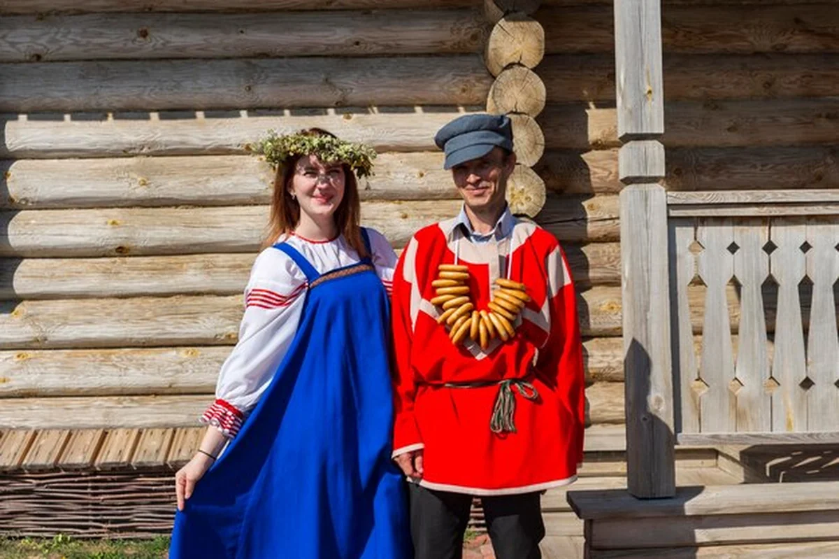 Mężczyzna i kobieta w tradycyjnych ubraniach przed drewnianą ścianą