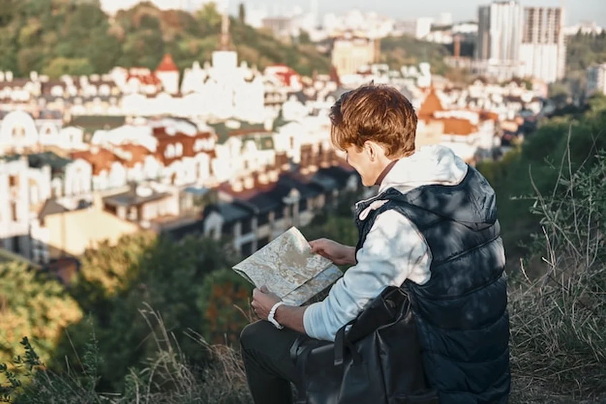 Młody bloger turystyczny bada widok z tyłu mapy