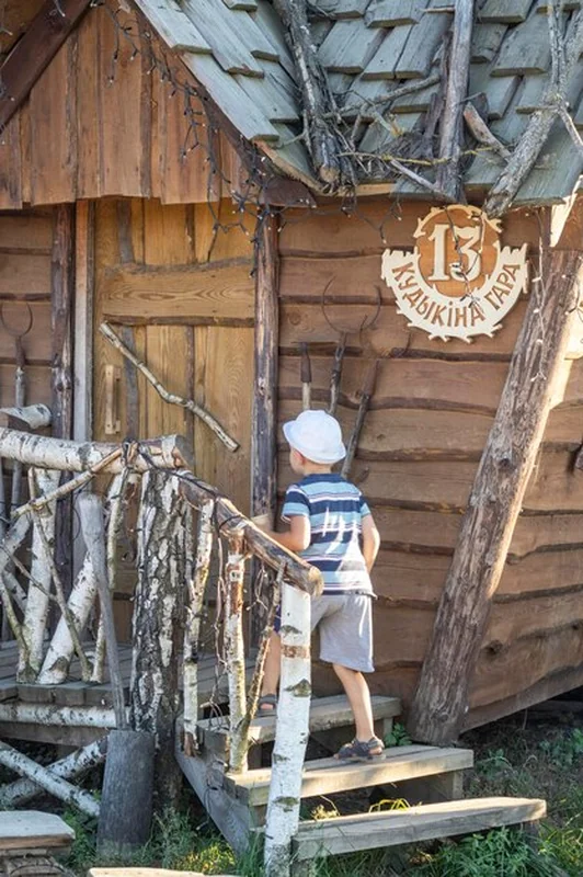Chłopiec wchodzący do drewnianej chaty w wiosce
