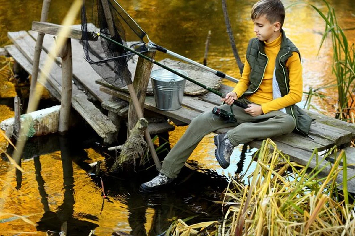 Chłopiec łowi rybę z drewnianego pomostu