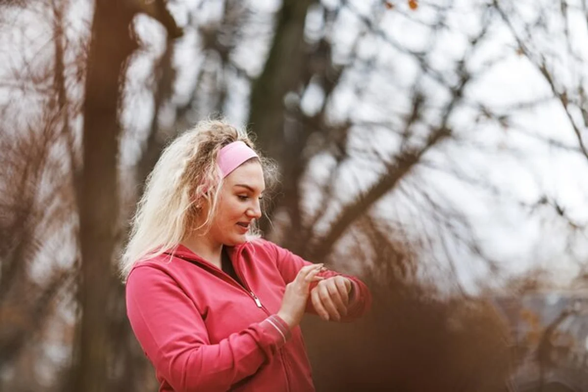 Kobieta sprawdzająca tracker fitness podczas treningu w parku