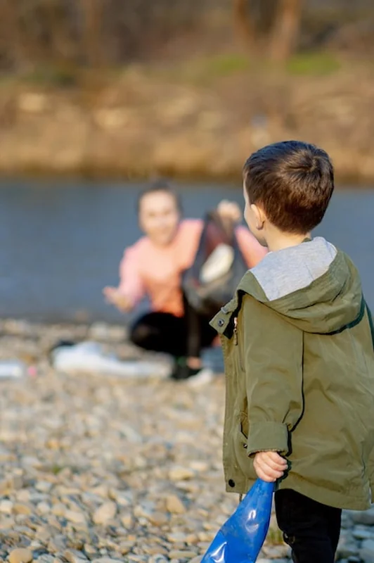 Kobieta z synem zbierają plastikowe śmieci na rzece
