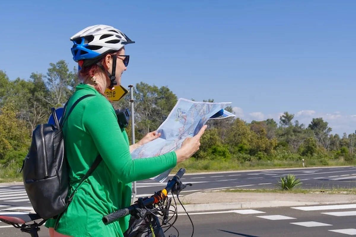 Turystyczna dziewczyna na rowerze oglądająca mapę