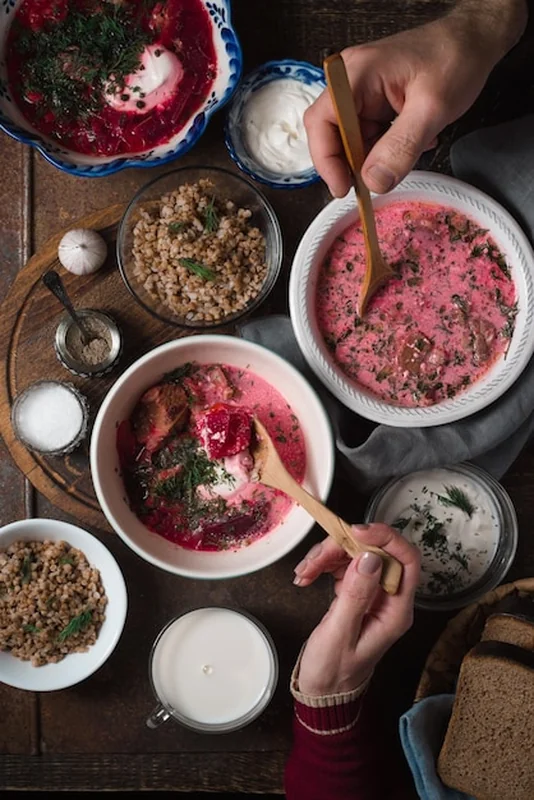 Borszcz z grzybkiem, kwaśną śmietaną, chlebem i ciastami mięsnymi na drewnianym stole